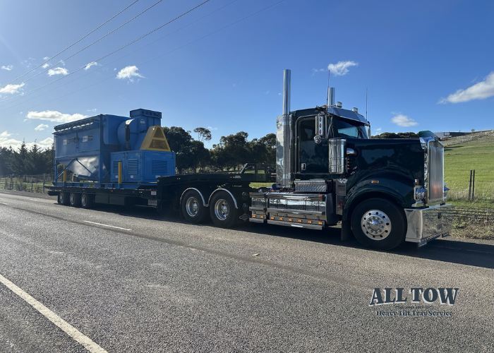 Kenworth tilt tray truck hauling industrial equipment for construction project in Melbourne
