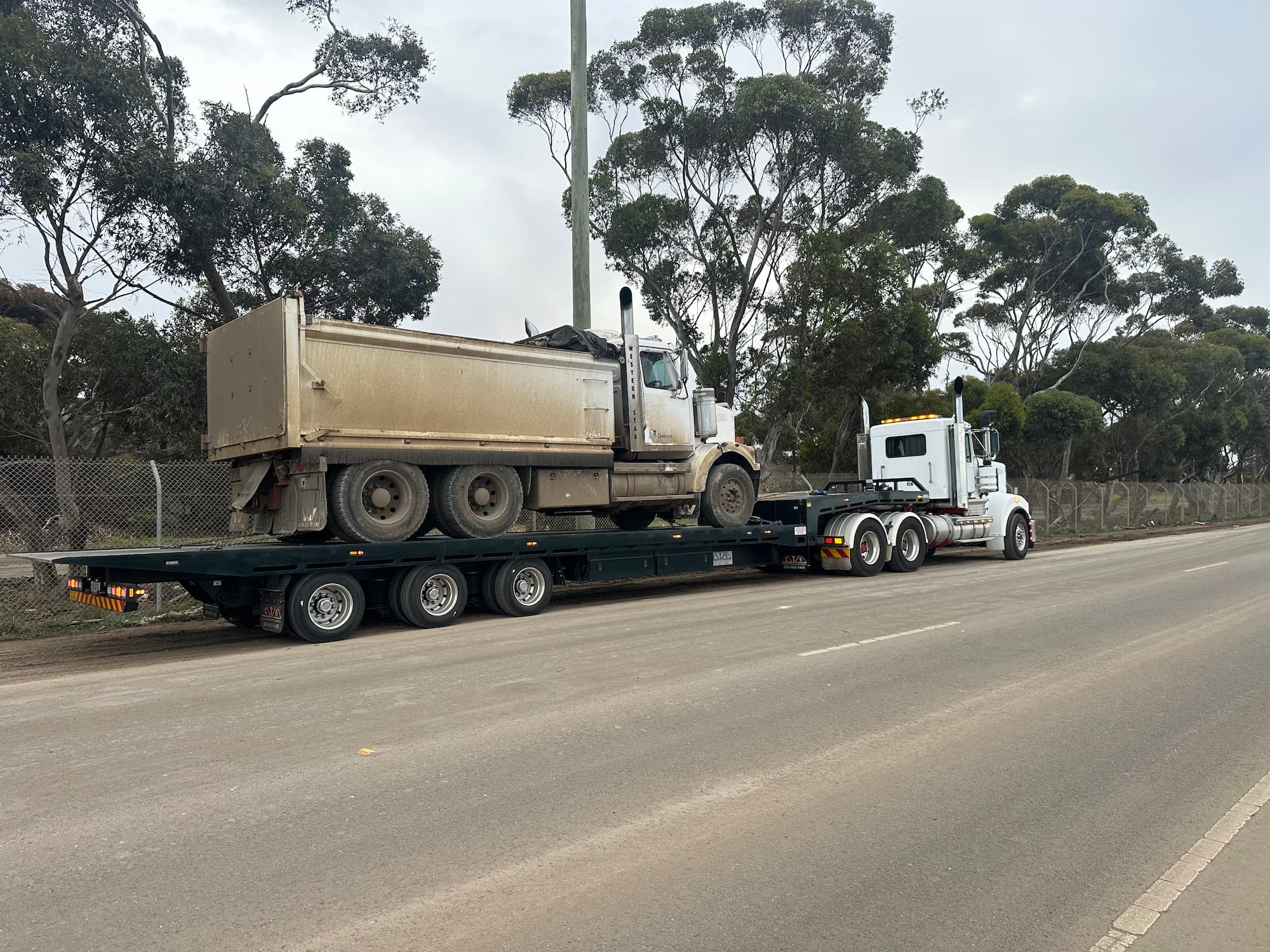 Heavy tilt tray towing tipper truck on flatbed trailer in Melbourne