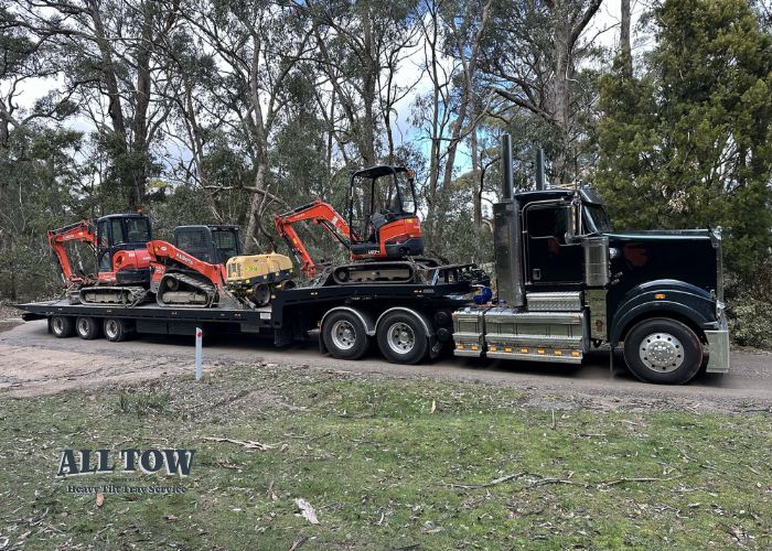 Kenworth tilt tray truck transporting excavators and machinery in Melbourne