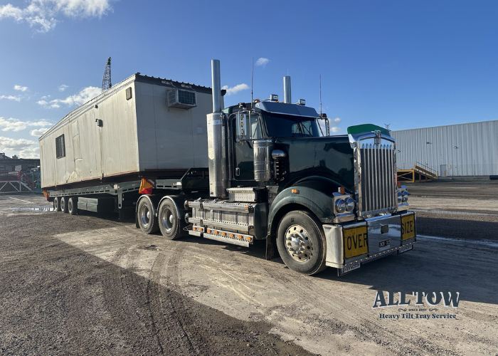 Kenworth tilt tray truck carrying portable building in Melbourne industrial area